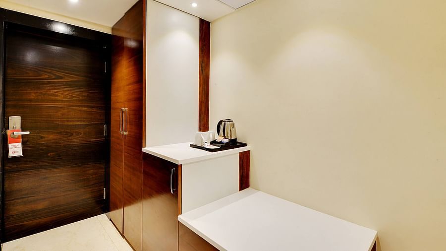 Cupboard in a room with attached table space and an electric kettle.