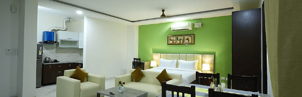 A hotel suite with a green accent wall, living area, dining table and an open kitchenette - Lime Tree Golf View, Golf Course Road