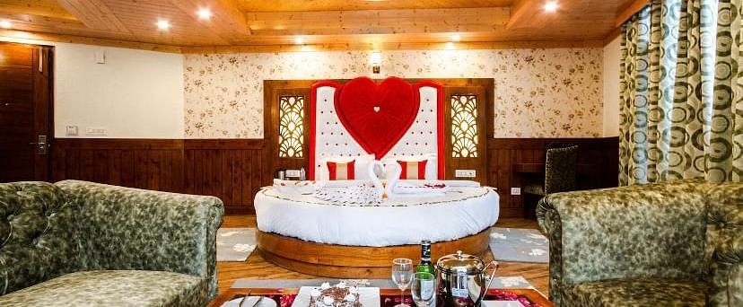 A cosy and inviting hotel room with a circular bed, comfortable sofas, and a romantic heart-shaped decoration | DLS La Serene Manali