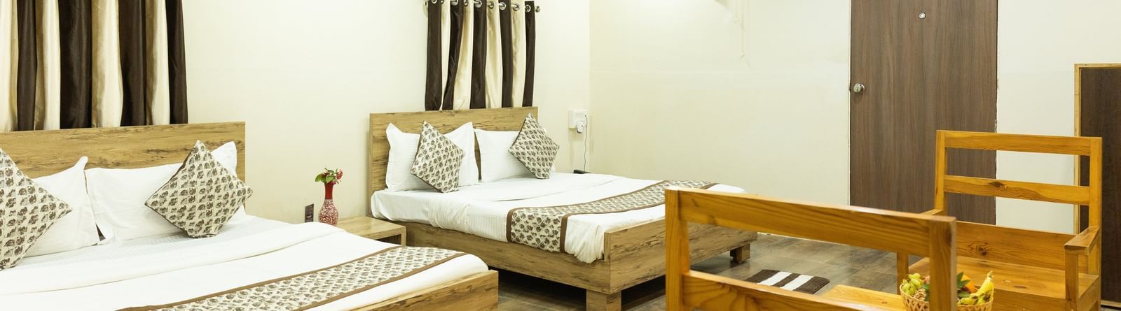 A guest room with two beds, a wooden dining set and ceiling lights at Daksh Resort & Amusement Park.