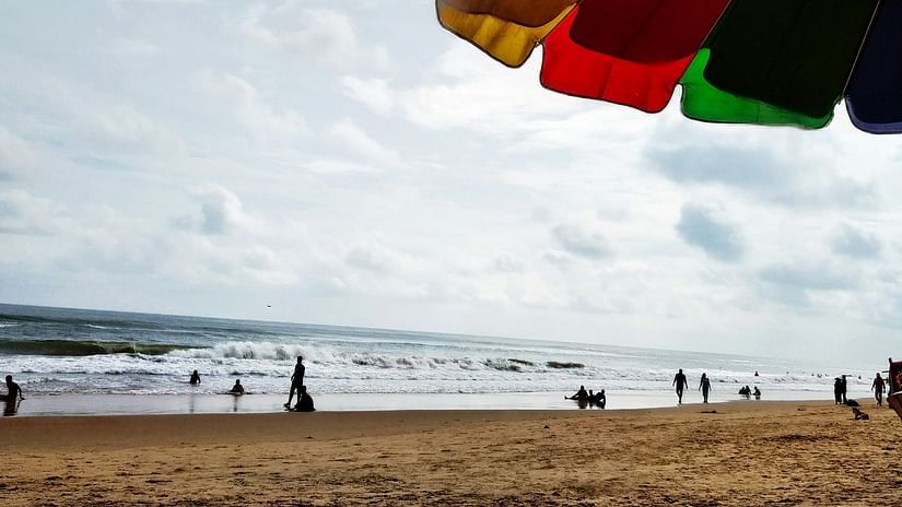View from the shore of the beach with a umbrella in the frame.