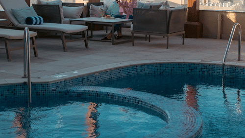 Poolside seating with patio and city views at La Maison Hotel, Doha.