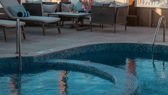 Poolside seating with patio and city views at La Maison Hotel, Doha.