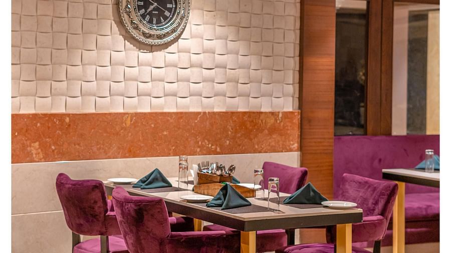 Comfortable cushioned chairs and a beautifully set table with culinary delights await guests at Courtyard Fine Dine, Crescent Spa & Resort, Indore