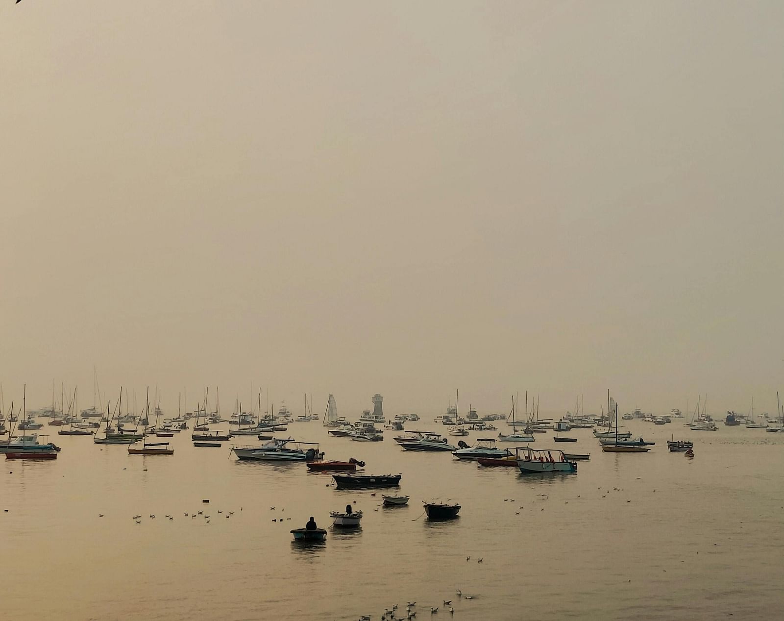 A still ocean with several boats during the evening floating on the ocean bed.
