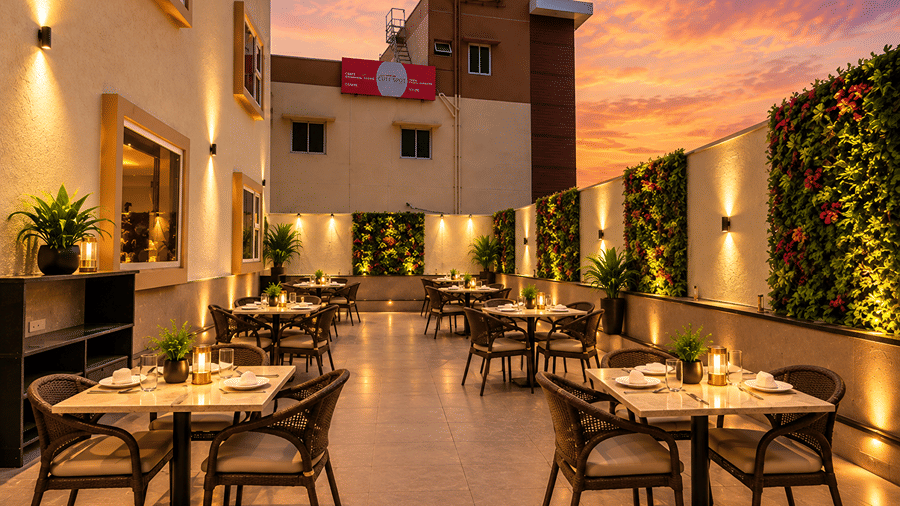 Outdoor rooftop dining area with arranged tables and chairs under twilight sky at Bhavani's Vista By Icon, Hosur.   