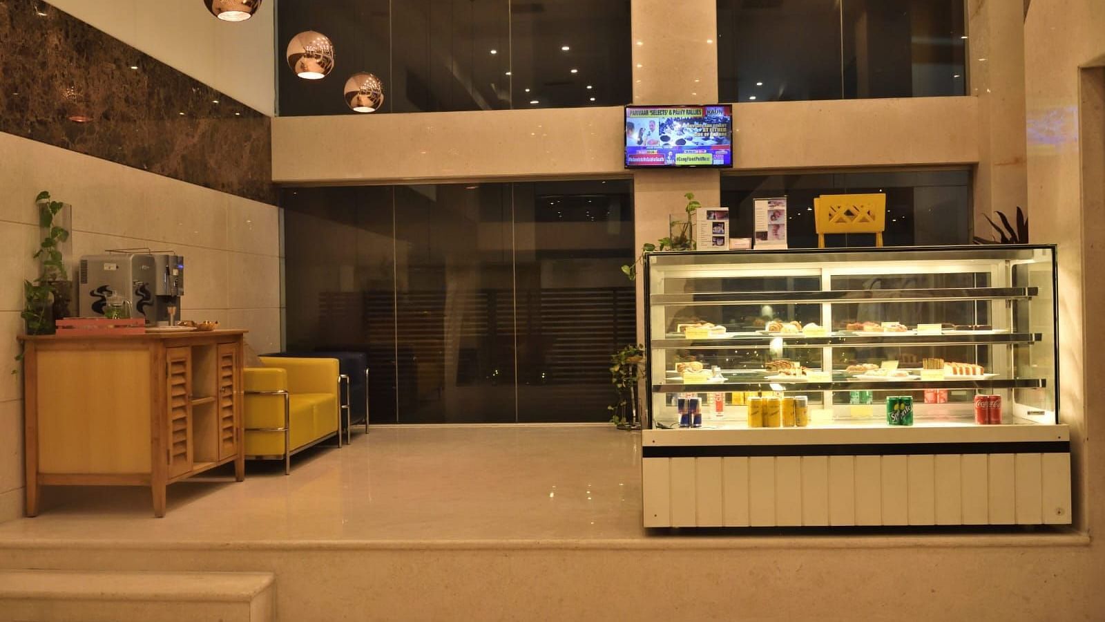 The Lobby Bake House features a display fridge with food, seating, and warm lighting, suggesting a welcoming atmosphere at The Cunningham Hotel