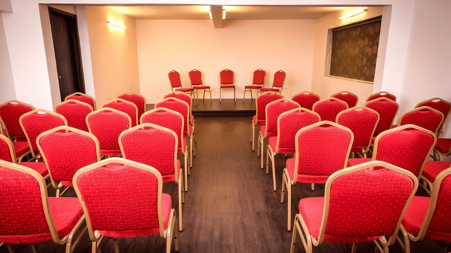 A event space of the hotel adorned with red and gold chairs arranged in a classroom style seating.