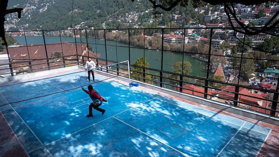 Two men playing badminton with a river view beside them at Himalaya Hotel, Nainital