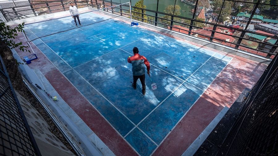 Two men playing badminton with a river view beside them at Himalaya Hotel, Nainital