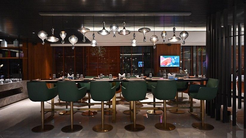 A sleek bar lounge featuring green bar stools and ambient lighting, designed for upscale dining and drinks.