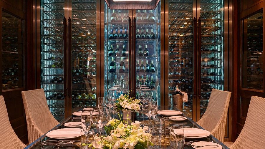image of a beautifully set dining table along with the wine cellar in the background - Maikhao Dream Villa Resort & Spa, Phuket 