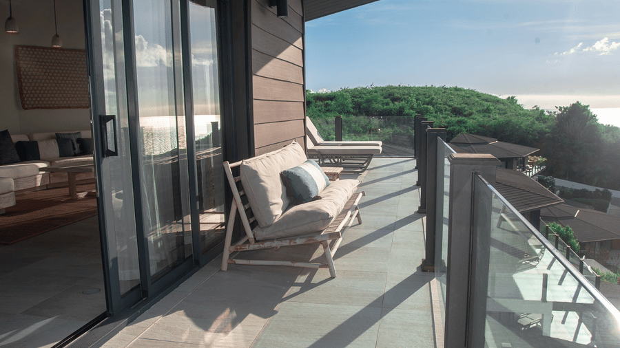 A balcony area with sliding glass doors, a sofa and a view of the greenery at Tamarind Hills Resort and Villas, Antigua.