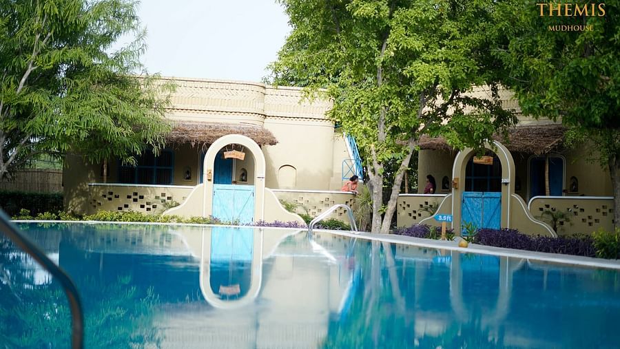 A pristine swimming pool surrounded by trees at Themis Mudhouse - A Nature's Retreat Resort & Wellnesss