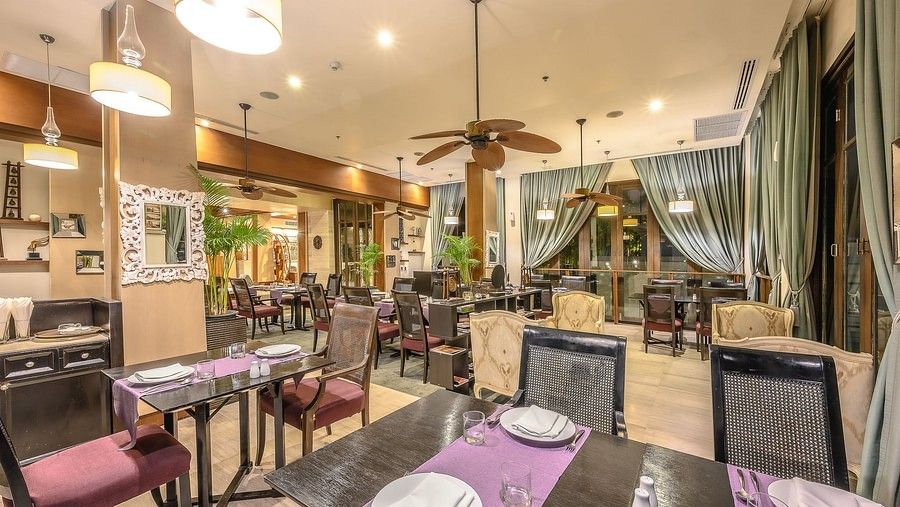image of the indoor dining outlet with bright lighting and olive green coloured curtains - Maikhao Dream Villa Resort & Spa, Phuket