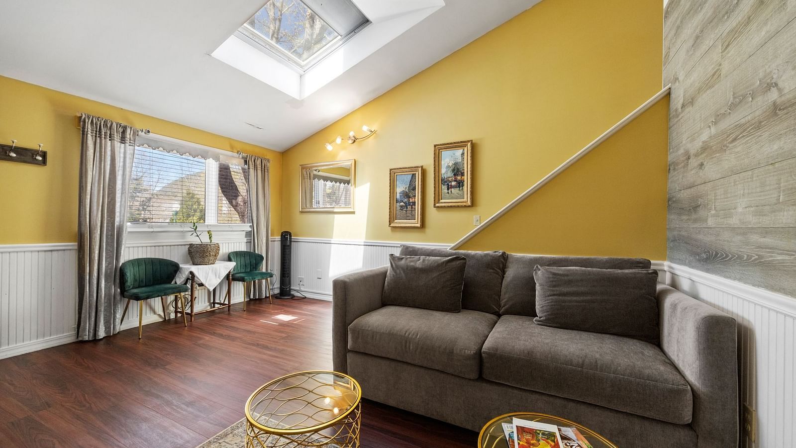 Modern living room at Hartstone Inn with a skylight, yellow walls, a gray couch, and a round wicker coffee table