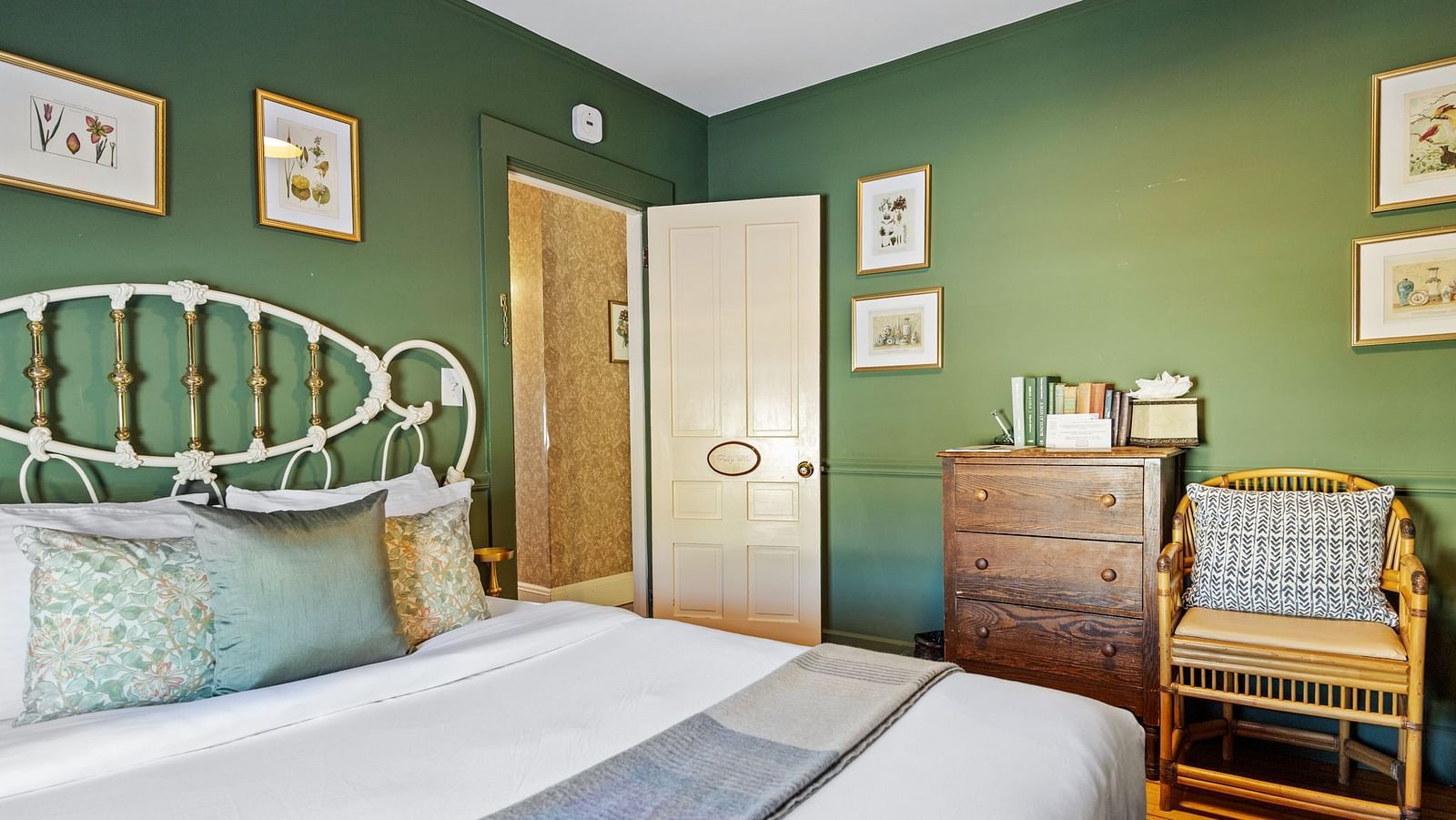 Green-themed bedroom with antique furniture and metal bed frame at Hartstone In