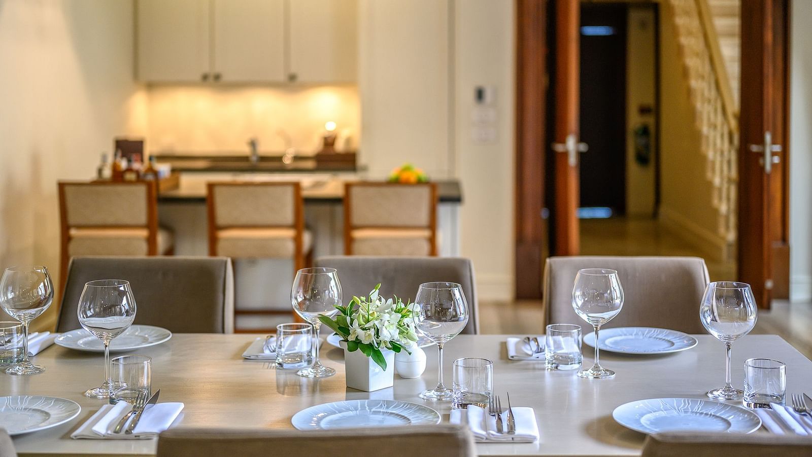Elegant dining table set with plates, glasses and cutlery in a modern kitchen space - Maikhao Dream Villa Resort & Spa, Phuket