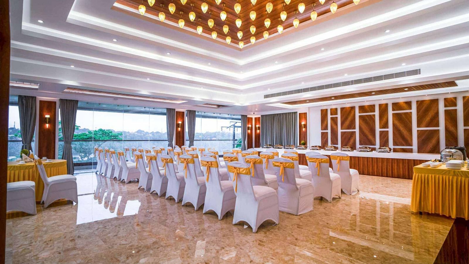 A well-lit event hall at Mansha Palace is arranged with rows of draped chairs facing a stage area.