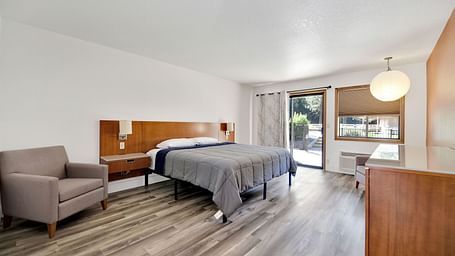 A view of a room at Amador Hotel with a double bed and a sofa chair.