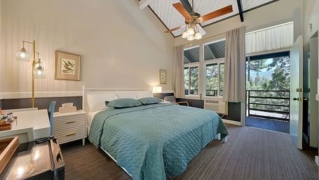 A view of a room at Narrow Gauge Inn with a double bed and sliding doors opening to a balcony.