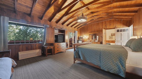 Side view of Mission Suite at Narrow Gauge Inn, featuring wooden ceiling, carpeted flooring, ample space, a TV, and a plush bed.