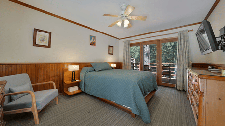 A view of a room at Narrow Gauge Inn with a double bed and sliding doors opening to a balcony.