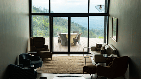 A modern lounge area with dark armchairs and a large glass wall looking out over a mountain valley at Stanley Revelation.