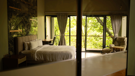 A bedroom featuring a large bed and glass doors that open onto a balcony with forest views at Stanley Revelation.