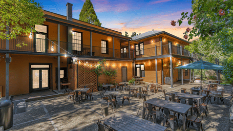 early evening view of the backyard of The Groveland Hotel with tables and chairs.