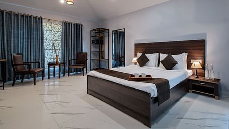 A room at Valley by Grassfield featuring a bed and a seating area with two chairs and a table.