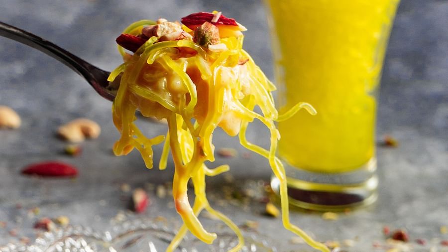  Fork lifting strands of saffron rice from a plate, served with garnish and a beverage.