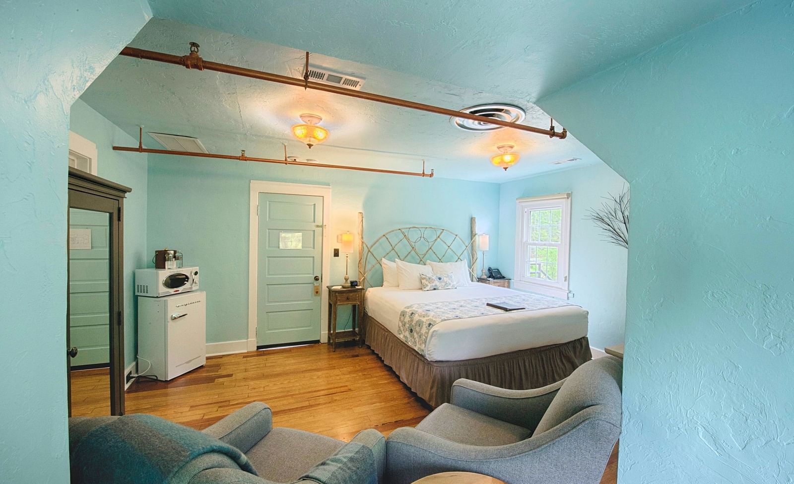 a beautiful room with calming tones featuring a double bed and a mini refrigerator in the room - Historic Tapoco Lodge