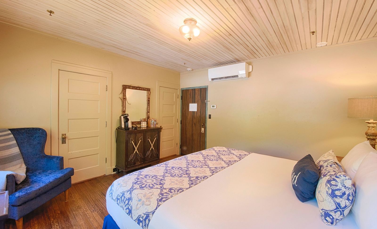 side view of a bedroom featuring a double bed along with a blue coloured arm chair and a wall mounted split air-conditioner - Historic Tapoco Lodge