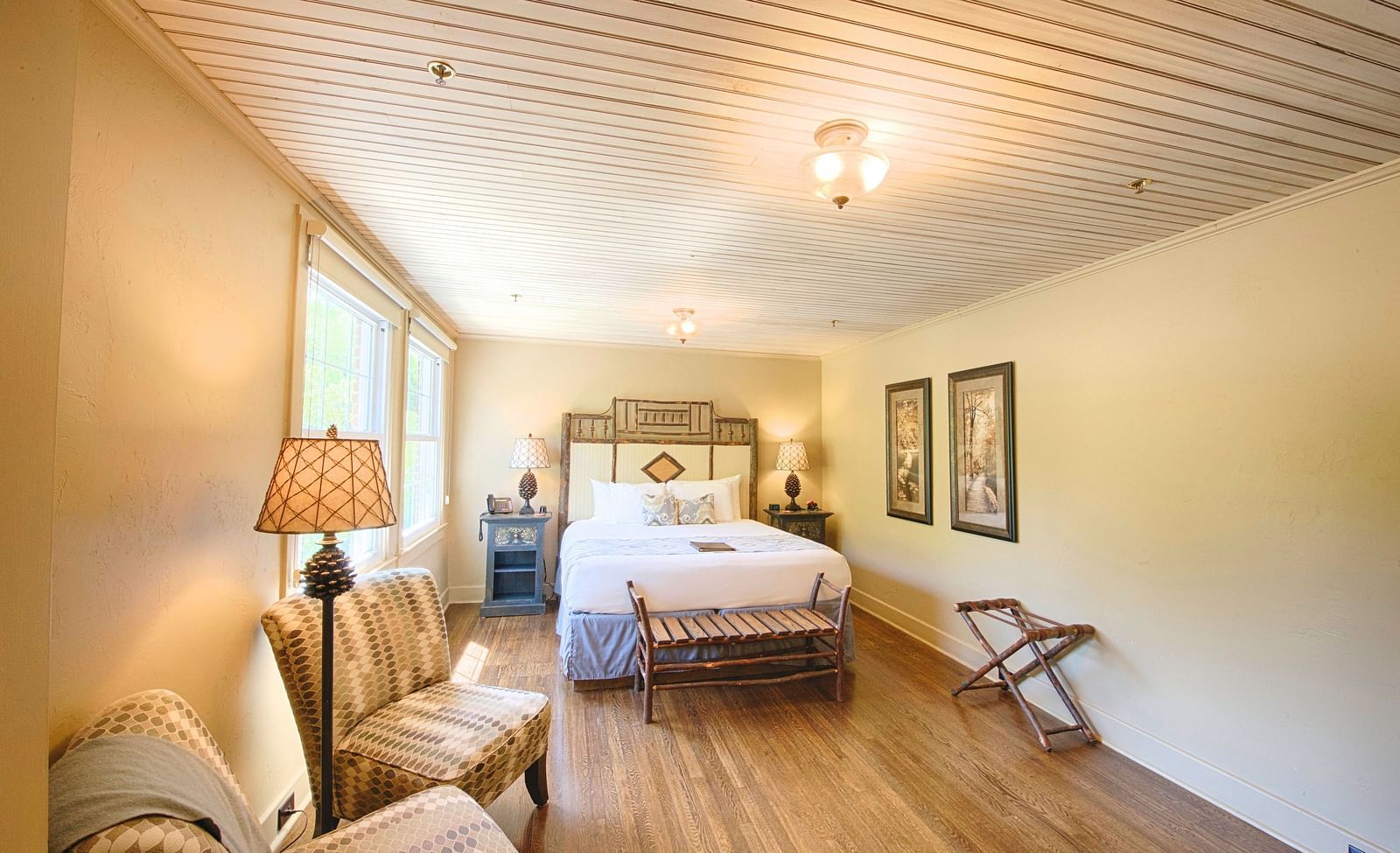 full view image of a bedroom with modern furnishings featuring a double bed along with two cushioned armchairs - Historic Tapoco Lodge