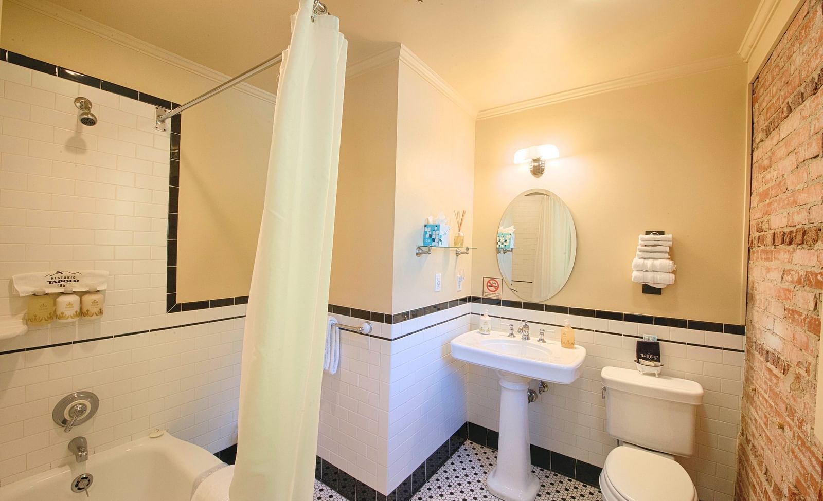 a bathroom featuring a commode along with wash basin with a circular mirror above it - Historic Tapoco Lodge