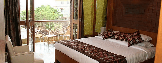 Room featuring a double bed and a balcony with seating area