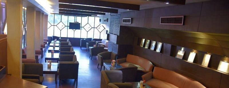 A cosy seating area with rustic interiors and brown leather couches - Hotel Gold, Panipat