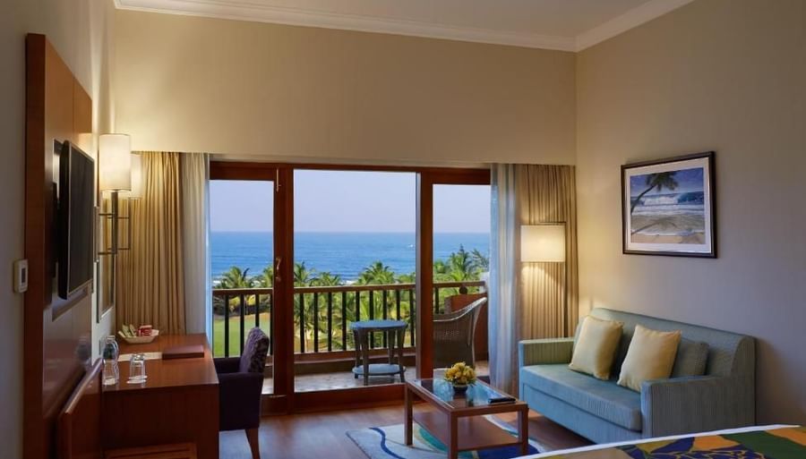 a double bed with a tv, sofa and a painting in view inside one of the rooms - Caravela Beach Resort Goa
