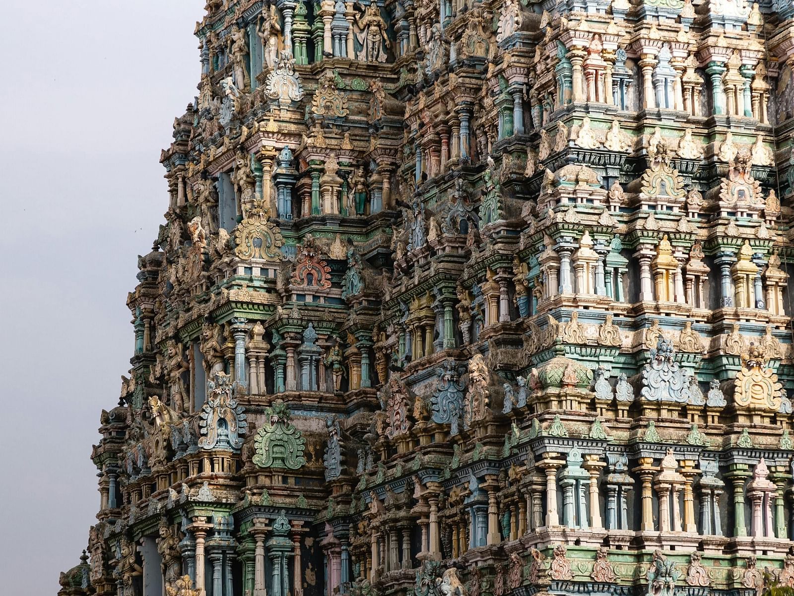 A wide view of the temple featuring intricate stone carvings on the top, showcasing detailed architectural design with the dark clouds in the background.