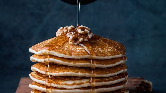 maple syrup being poured on pancakes