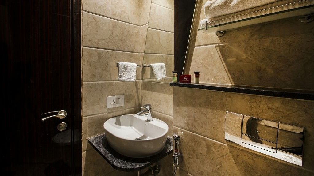 Standard room bathroom with sink, and towel on the wall at Art Boutique Hotel, Hyderabad
