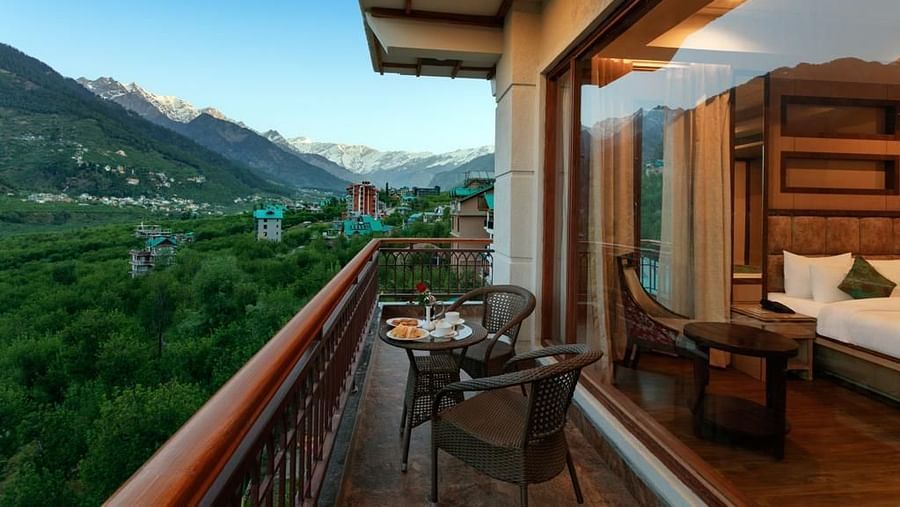 Suite in Manali with an attached balcony overlooking the mountains and greenery
