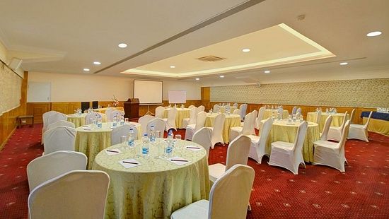 An energetic image of the inside view of a banquet hall showing the chairs and round tables arranged for a conference - Monarch Hotels