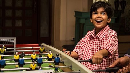 Happy child playing foosball in a recreational area.