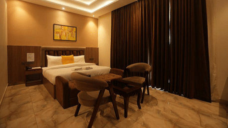 Suite of Lime Tree Hotels & Service Apartment Private Limited featuring dark curtains, a dining table, and a bed.