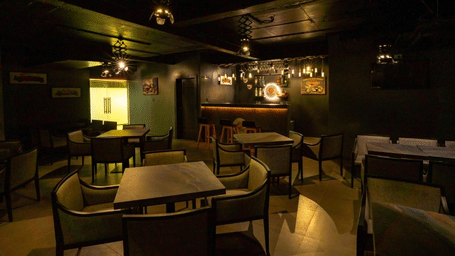 Madhuram bar featuring a dim-lit room with neatly arranged dining tables and chairs | Regency Palani by GRT Hotels