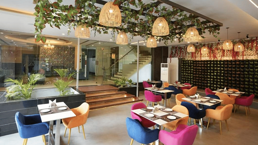 A dining area with hanging decorations, colourful chairs, and set tables, creating a lively atmosphere - VITS Gurugram