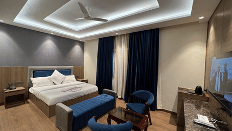 Suite of Lime Tree Hotels & Service Apartment Private Limited featuring navy blue chairs, a bed, and a work desk.