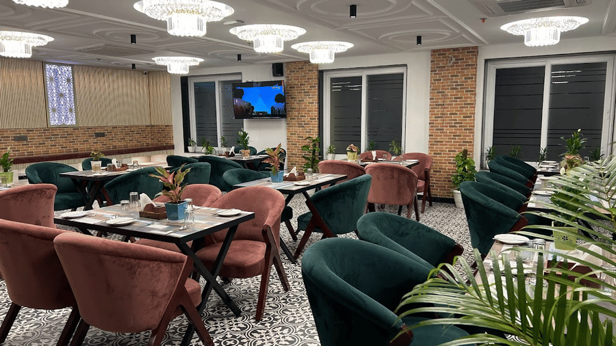 Restaurant of Lime Tree Hotels & Service Apartment Private Limited featuring green chairs, dining tables, and chandeliers.